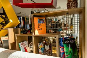 a book shelf with books and a bird cage at Motel One Köln-Mediapark in Cologne