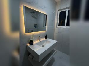 a white bathroom with a sink and a mirror at Marra’s Rooms in Durrës +19 photos