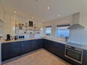 a large kitchen with black cabinets and a stove at Vakantiewoning "In Between" in Oostkapelle