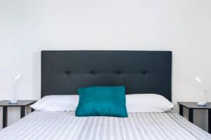 a bed with a black headboard and a green pillow at Casa dos avós in São Vicente +75 photos