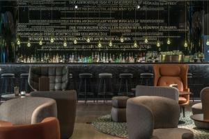 a bar with bar stools and a wall of bottles at Motel One Dresden-Palaisplatz in Dresden