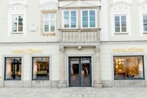 a white building with windows and a store front at Motel One Linz-Hauptplatz in Linz