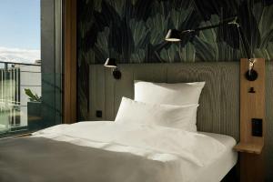 a bedroom with a white bed and a window at The Cloud One Düsseldorf-KöBogen in Düsseldorf