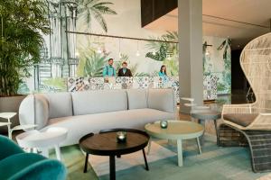 a living room with a couch and tables and people at Motel One Barcelona-Ciutadella in Barcelona