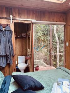 a bedroom with a bed and a large window at Cabana da Árvore e Cabana Retrô - ForestPlace in Monte Verde