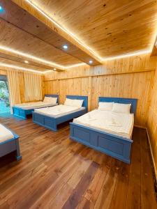 three beds in a room with wooden walls at Homestay CÂY THỊ in Tây Ninh
