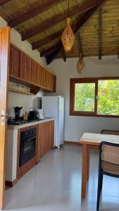 a kitchen with a white refrigerator and a table at Vila Baião - Casa Luiz Gonzaga in Itacaré