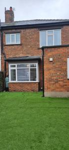 a brick house with a green lawn in front of it at Sandringham House in Stockton-on-Tees