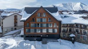 a building covered in snow with mountains in the background at MontiSio Boutique Hotel in Gudauri