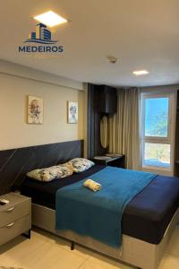 a bedroom with a bed with blue sheets and a window at Apartment 201 / Oceanfront / Mirrored Bed / Kitchen in João Pessoa