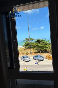 a window with a view of a parking lot with cars at Apartment 201 / Oceanfront / Mirrored Bed / Kitchen in João Pessoa +7 photos
