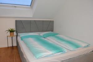 a bed with blue and white sheets and a window at Modernes Dachgeschoss in Augsburg