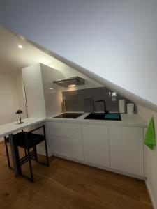 a kitchen with white cabinets and a sink and a table at Modernes Dachgeschoss in Augsburg