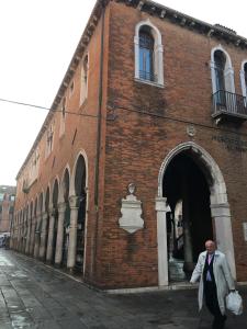 un hombre caminando delante de un edificio de ladrillo en Antico Mercato, en Venecia