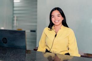 a woman sitting at a desk with a laptop computer at Hotel Marco Polo Rodadero in Santa Marta