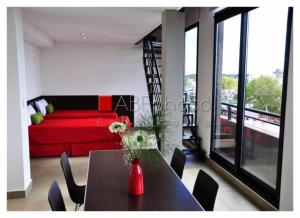 a room with a red bed and a table with chairs at Apart Maral Zárate in Zárate