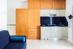 a kitchen with wooden cabinets and a blue couch at Aparthotel Terme Grado - Private Parking in Grado