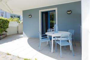 a table and chairs on a patio with a blue wall at Aparthotel Terme Grado - Private Parking in Grado +37 photos