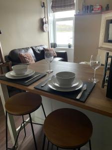 a kitchen with a table with plates and wine glasses at An Cuilidh in Port Bannatyne +11 photos
