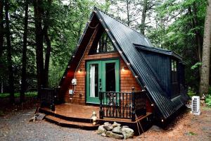 a small cabin in the woods with a green door at Romantic AFrame Cabin with Firepit, BBQ in Pocono Pines