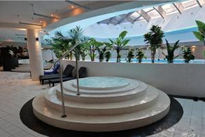 a fountain in the middle of a lobby with palm trees at FRANKO APARTAMENTS - Hanza Tower in Szczecin
