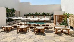a patio with tables and chairs and a pool with umbrellas at Hotel Clark in Los Angeles