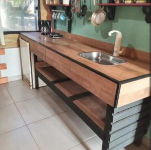 a kitchen with a wooden counter with a sink at Chalé amora Analândia in Analândia
