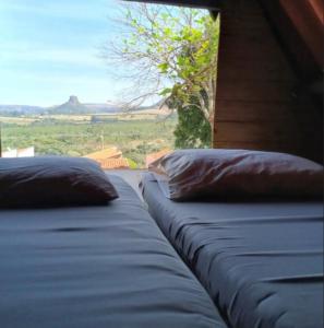 a bed with two pillows and a window with a view at Chalé amora Analândia in Analândia