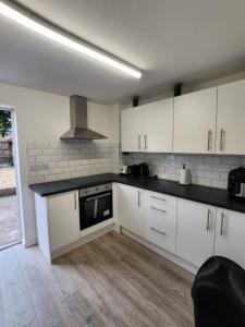 a kitchen with white cabinets and a stove top oven at Ensuite premier rooms in Basildon