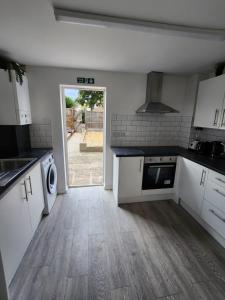 a kitchen with white cabinets and a door to a yard at Ensuite premier rooms in Basildon