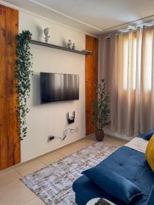 a living room with a blue couch and a tv on a wall at Apê 302 prox ao SESC in Franca