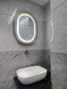 a bathroom with a white sink and a round mirror at Hotel Red Rose in Vadodara