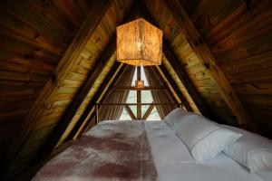 a large bed in a wooden room with a lamp at Olivas Eco Chalé in Pouso Alto