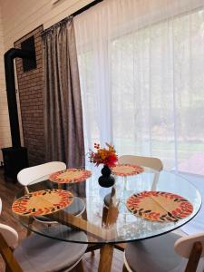 a glass table with two chairs and a vase with flowers at Котедж RIVERHILL 2-4 осіб in Slavske
