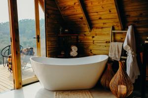 a white bath tub in a room with a window at Olivas Eco Chalé in Pouso Alto +58 photos