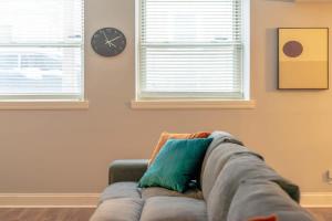 a couch in a living room with a clock on the wall at Lovely CWE 2BR with Private Parking ABODEbucks in Saint Louis