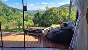 a man laying on a ball laying on a bed on a porch at Refúgio na Serra com Pôr do Sol in Feliz