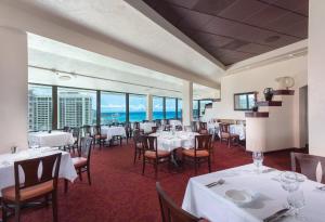 a restaurant with white tables and chairs and windows at Waikiki Marina Resort at the Ilikai in Honolulu