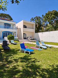 a group of chairs sitting in the grass in front of a building at Departamentos blue Turquesa in Bacalar