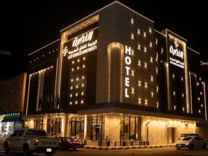 a lit up building with cars parked in front of it at النخبة الرفيعة للشقق المخدومة in Al Qurayyat