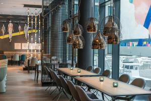 a dining room with tables and chairs and chandeliers at Motel One Berlin-Alexanderplatz in Berlin