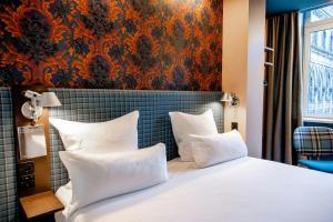 a bedroom with a large bed with white pillows at Motel One Edinburgh-Princes in Edinburgh