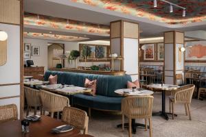 a restaurant with tables and chairs and a blue couch at Protea Hotel by Marriott Cape Town Sea Point in Cape Town