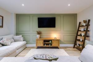 a living room with a couch and a tv on a wall at Rock Mill - The Penthouse Suite in Stony Middleton