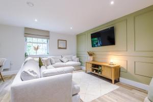 a living room with two white couches and a tv at Rock Mill - The Penthouse Suite in Stony Middleton