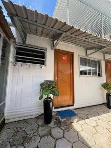 a house with a wooden door and a potted plant at Vila do Chave Dona Florinda 14 in Itajaí