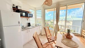 a kitchen with a table and chairs and a large window at Maemora - Studio in Les Trois-Îlets