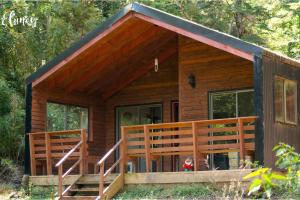 a cabin in the woods with a deck and stairs at Cafeteria y cabañas Eluney - Koigue in Pucón
