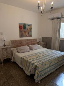 a bedroom with a bed and two night tables and a painting at Elportal in Alta Gracia