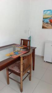 a wooden table with a chair and a painting on the wall at Kit 400mts da praia in Bertioga +2 photos